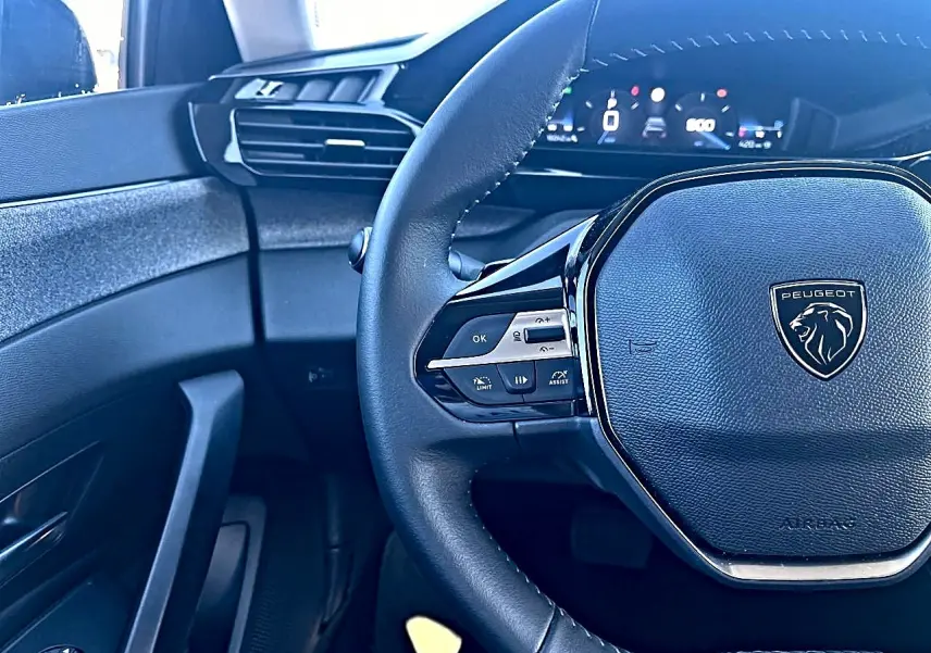 Vue rapprochée du volant noir multifonction et du tableau de bord numérique de la Peugeot 308 2025 côté conducteur.