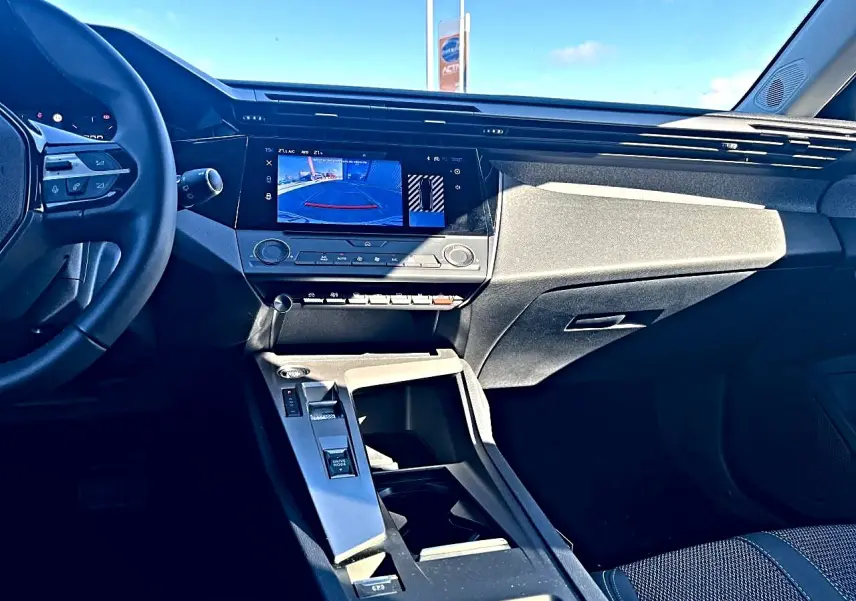 Vue intérieure avant droite de la Peugeot 308 noire, écran tactile affichant la caméra de recul et console centrale moderne.