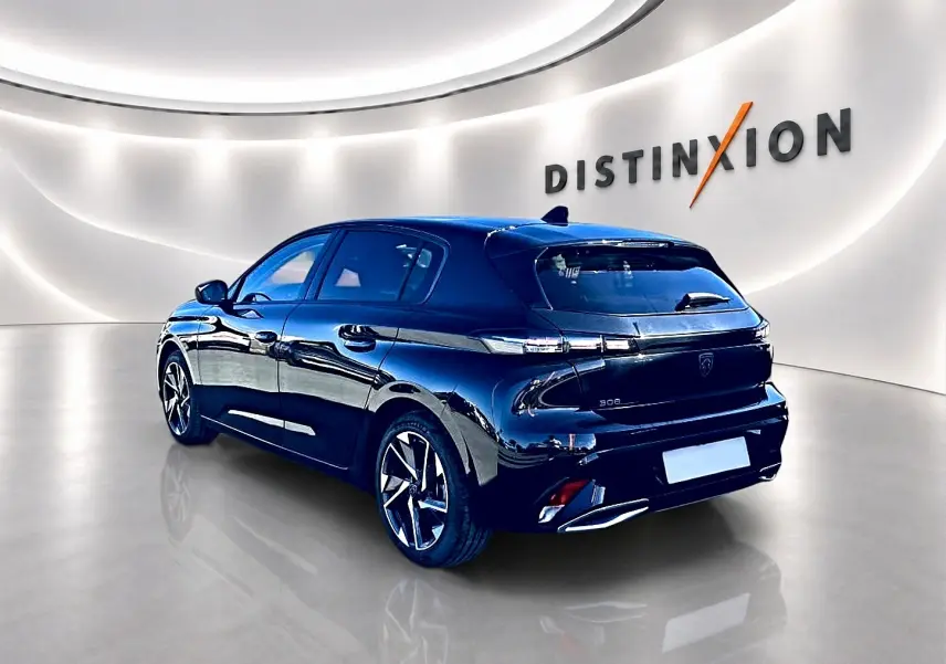 Peugeot 308 noire vue 3/4 arrière droit en intérieur, avec jantes alliage et feux arrière LED distinctifs.