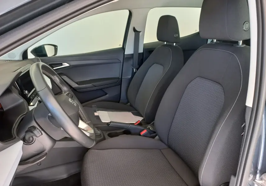 Vue intérieure côté conducteur de la SEAT IBIZA 2025 gris magnétique, montrant les sièges avant et le volant.