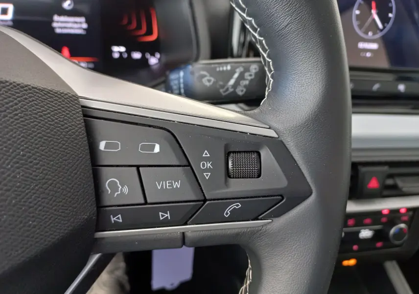 Gros plan sur le volant côté gauche de la SEAT IBIZA 2025 gris magnétique, avec commandes vocales et multimédia visibles.