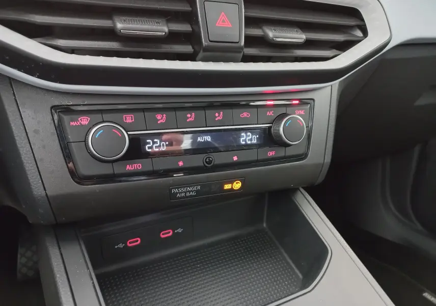 Vue rapprochée du tableau de bord du SEAT Ibiza 2025 gris magnétique, montrant la climatisation automatique et ports USB.