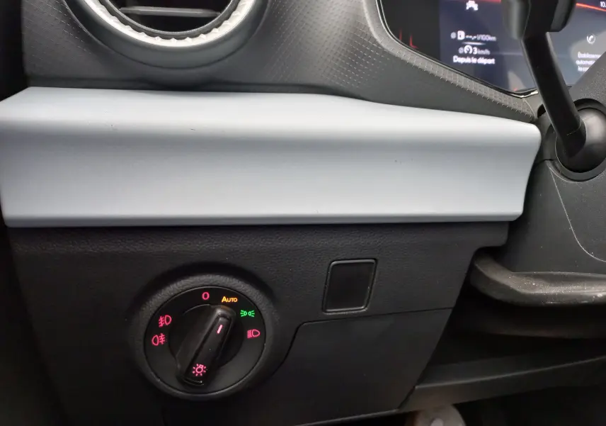 Détail intérieur du tableau de bord côté gauche d’une SEAT IBIZA gris magnétique 2025 avec commande des phares et aérateur rond.