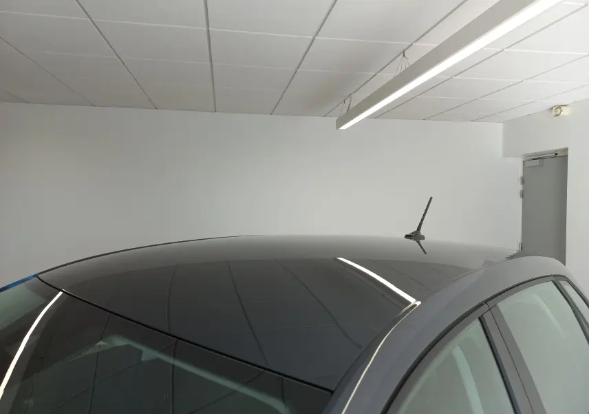 Toit panoramique noir brillant du SEAT Ibiza gris magnétique, vu en léger angle depuis l'arrière droit dans un intérieur blanc.