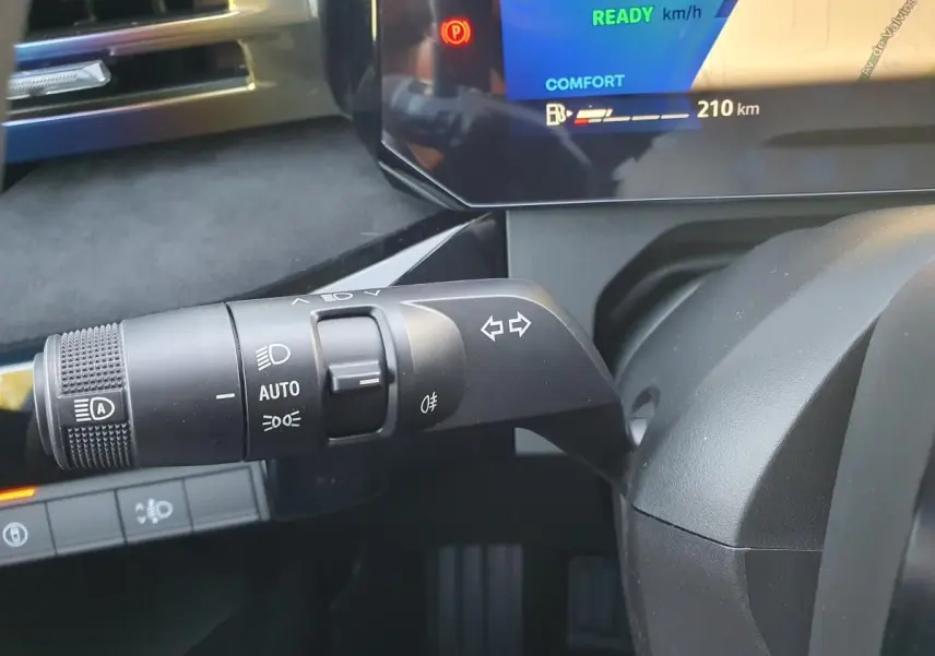 Gros plan sur la commande des feux et clignotants à gauche du volant dans l'habitacle de la Renault Clio VI hybride.