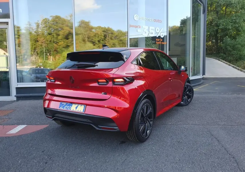 Vue 3/4 arrière droite de la Renault Clio VI rouge Absolu avec jantes alliage noires et toit noir brillant.