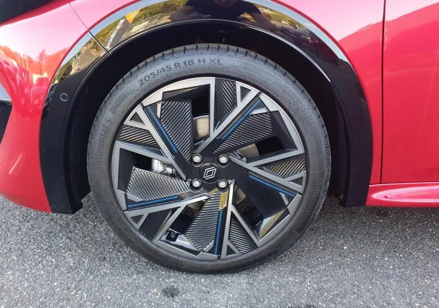 Gros plan sur la jante alliage diamantée 18” cosmic noire et grise du côté avant gauche d’une Renault Clio VI rouge absolu.