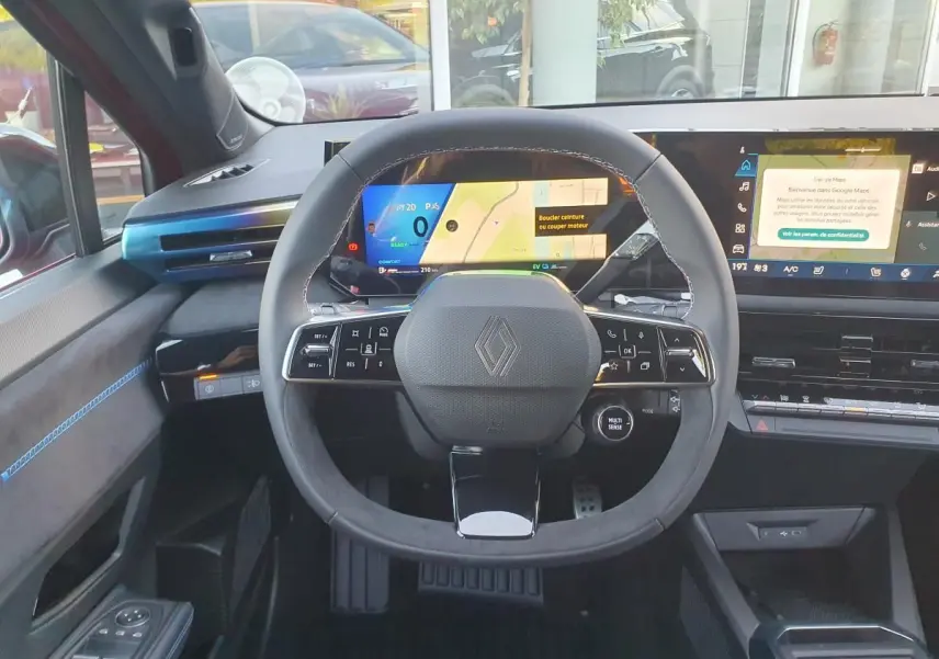 Vue frontale du tableau de bord de la Renault Clio VI hybride avec volant compact et écran numérique large.