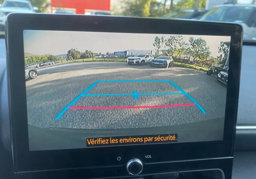Vue de l'écran de la caméra de recul d'une Toyota Yaris Cross gris atlas, affichant les lignes de guidage au parking.