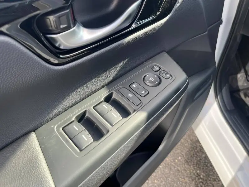 Vue rapprochée de la commande des vitres et rétroviseurs côté conducteur sur porte intérieure noire du Honda CR-V blanc.