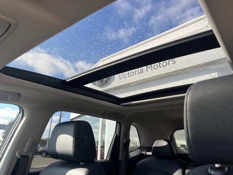 Vue intérieure du toit panoramique ouvert du Honda CR-V 2024 en cuir noir, avec ciel bleu visible à travers le verre.