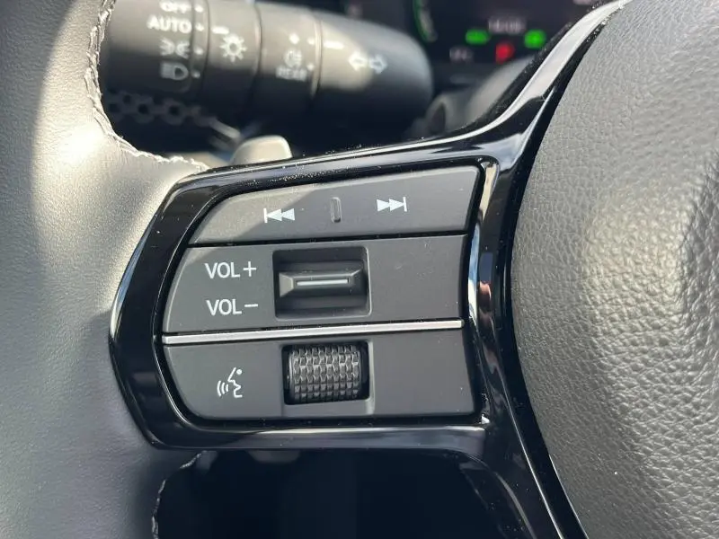 Gros plan sur les commandes audio au volant cuir noir du Honda CR-V 2024, avec molette de volume et boutons de navigation.