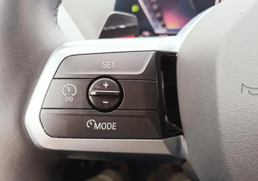 Gros plan sur le phare avant droit LED d'une BMW Série 1 gris Skyscraper avec toit noir, gouttes de pluie visibles.