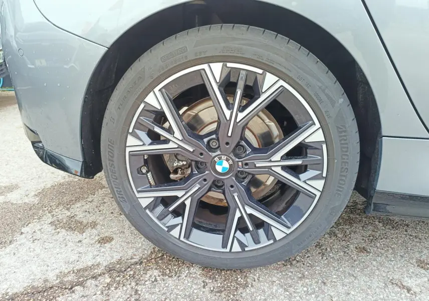 Coffre ouvert de BMW Série 1 gris, banquette arrière rabattue partiellement côté droit, vue depuis l'arrière.