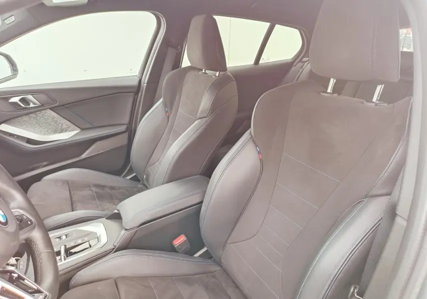 Vue intérieure arrière côté gauche de la BMW Série 1 120 M Sport gris Skyscraper avec sellerie Alcantara noire et surpiqûres bleues.