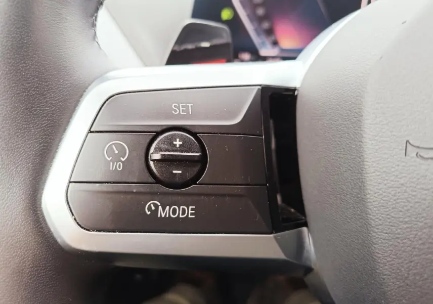 Gros plan sur les commandes de régulateur de vitesse au volant cuir noir de la BMW Série 1 2025.