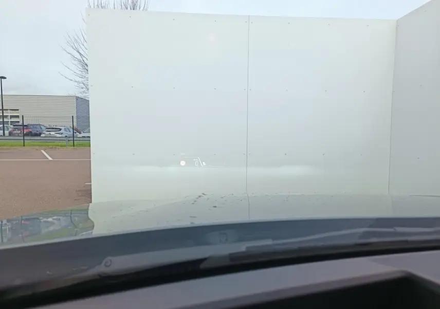 Vue depuis l’intérieur de la BMW Série 1 2025, toit gris Skyscraper avec affichage tête haute projeté sur le pare-brise.