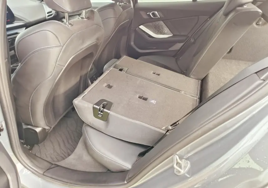 Vue côté droit de l’intérieur arrière de la BMW Série 1 gris Skyscraper, banquette rabattue et sellerie noire.