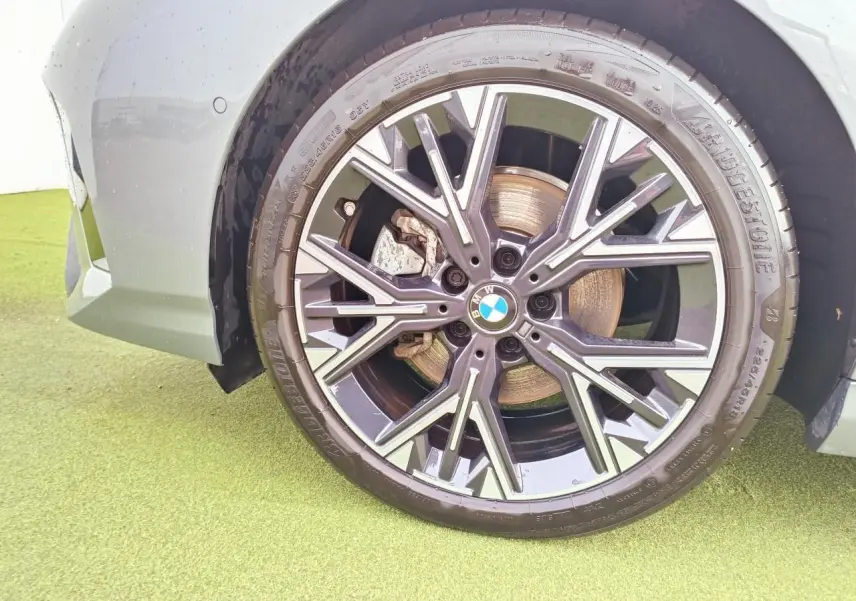 Gros plan sur la roue avant gauche d'une BMW Série 1 gris Skyscraper avec jante alliage 18 pouces style 975 M bicolore.