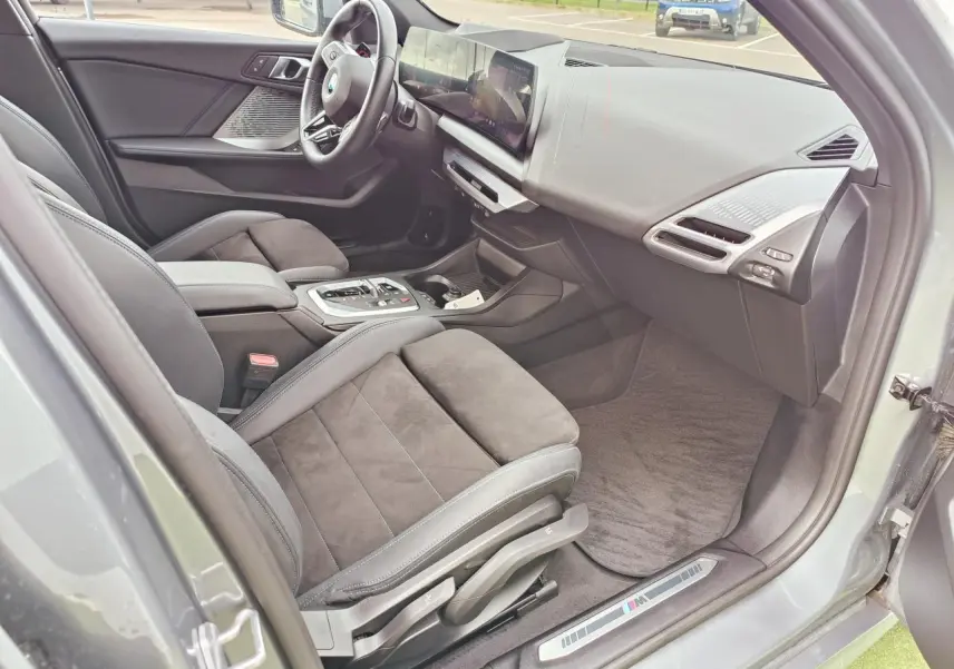 Vue 3/4 arrière droite d'une BMW Série 1 gris Skyscraper avec feux LED distinctifs et diffuseur noir brillant.