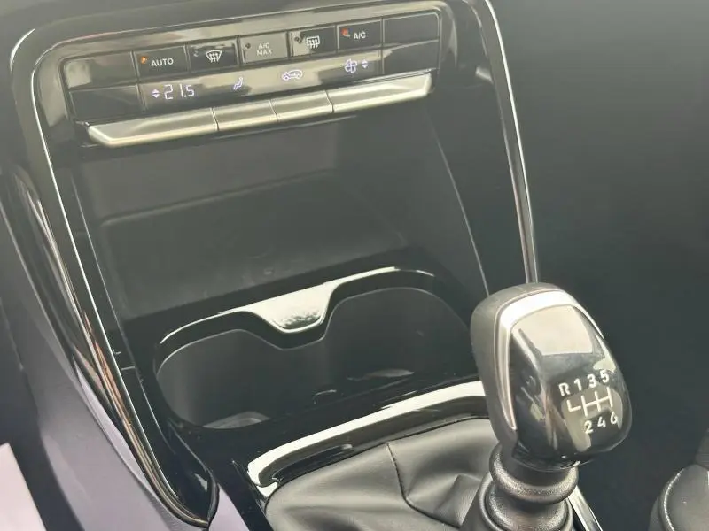 Gros plan sur la console centrale noire brillante de la Citroën C3 1.2 Turbo 100ch MAX avec levier de vitesses manuel et commandes climatiques.
