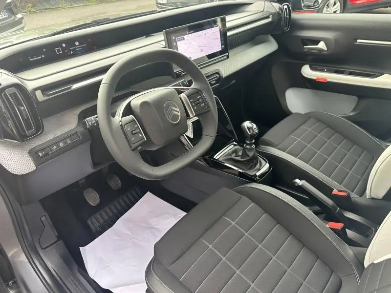 Intérieur avant de la Citroën C3 gris Mercury, vue côté conducteur montrant volant, écran tactile et sièges tissu noir.