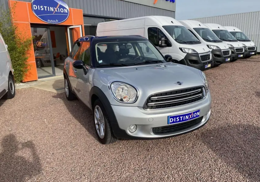 MINI Countryman gris clair en 3/4 avant droit avec toit noir et calandre chromée, stationnée devant un concessionnaire.