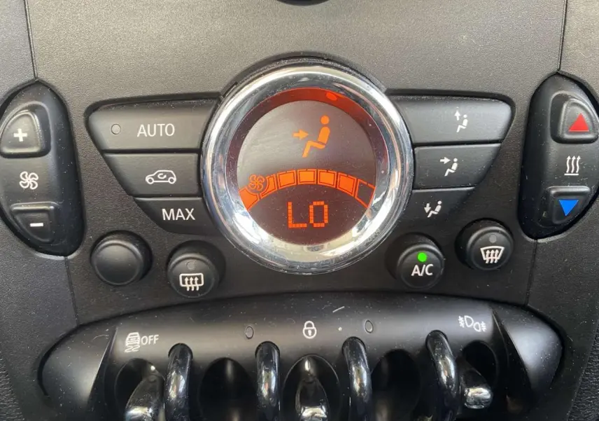 Gros plan sur les commandes de climatisation automatique avec affichage digital orange dans une MINI Countryman gris clair.