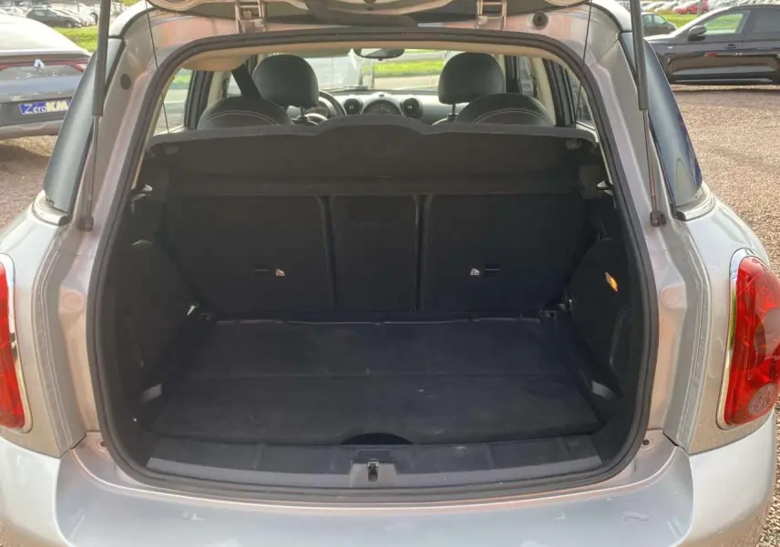 Vue arrière ouverte du coffre d'une MINI Countryman gris clair, montrant l'espace de chargement et la banquette arrière.