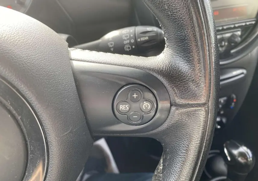 Gros plan sur le volant en cuir noir d'une MINI Countryman gris clair, avec commandes de régulateur de vitesse visibles.