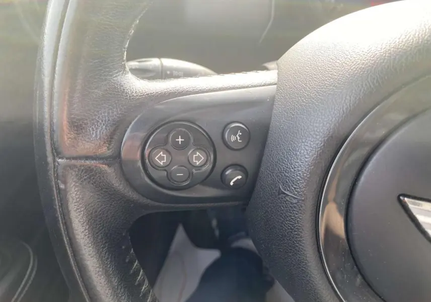 Gros plan sur les commandes du volant en cuir noir d'une MINI Countryman 2015, version Cooper D diesel.