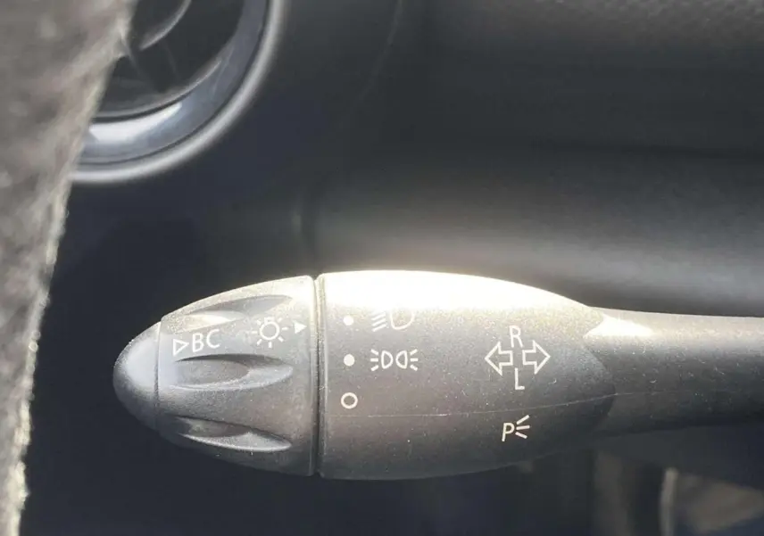 Gros plan sur la commande des clignotants et phares à gauche du volant dans l’habitacle d’un MINI Countryman gris clair.
