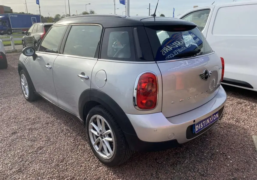 Vue 3/4 arrière droite d'une MINI Countryman gris clair avec toit noir et feux arrière ronds.