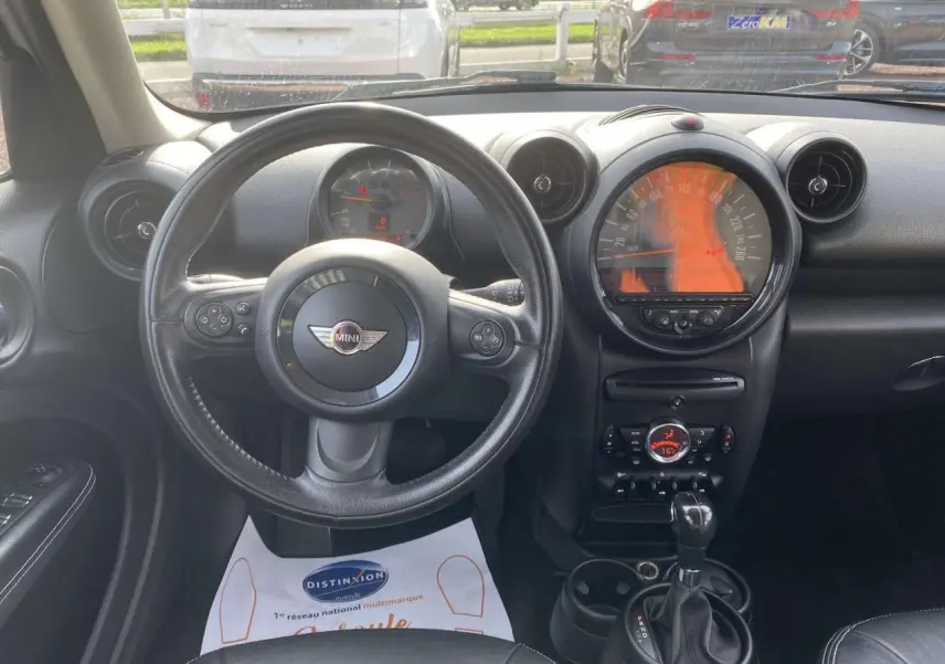 Vue intérieure frontale du tableau de bord et volant cuir noir d'une MINI Countryman gris clair de 2015 avec boîte auto.