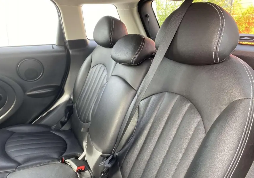 Vue intérieure des sièges arrière en cuir noir du MINI Countryman gris clair, avec ceinture de sécurité visible.