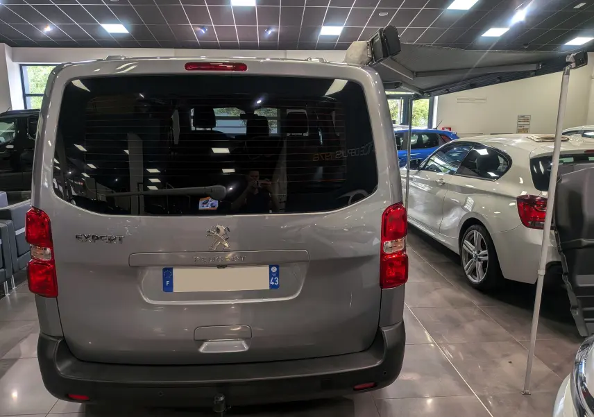 Vue arrière du Peugeot Expert Fourgon gris acier 2023 avec store latéral déployé en intérieur showroom.