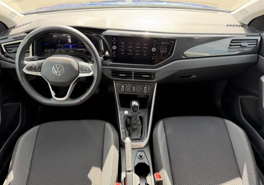 Vue intérieure avant du Volkswagen Taigo 2025 avec tableau de bord noir, volant cuir multifonctions et console centrale compacte.