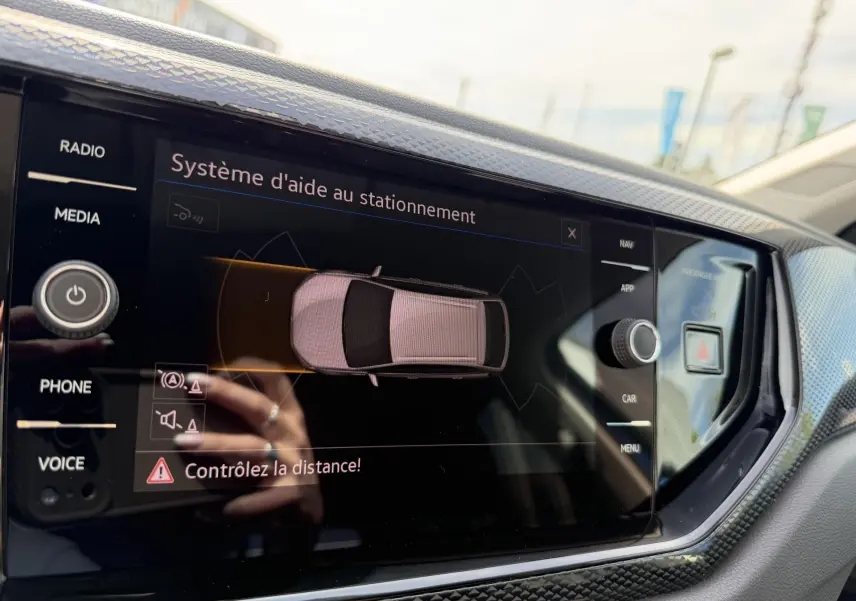 Écran tactile intérieur du Volkswagen Taigo bleu montrant le système d'aide au stationnement en vue de dessus.