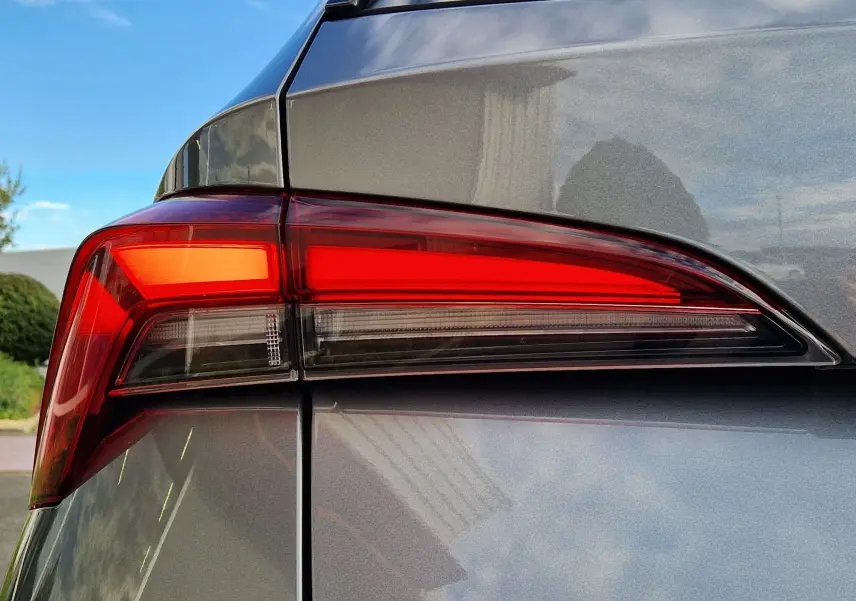 Gros plan sur le feu arrière droit d'un Skoda Kamiq 2024 gris graphite métal avec finition lisse et reflets brillants.