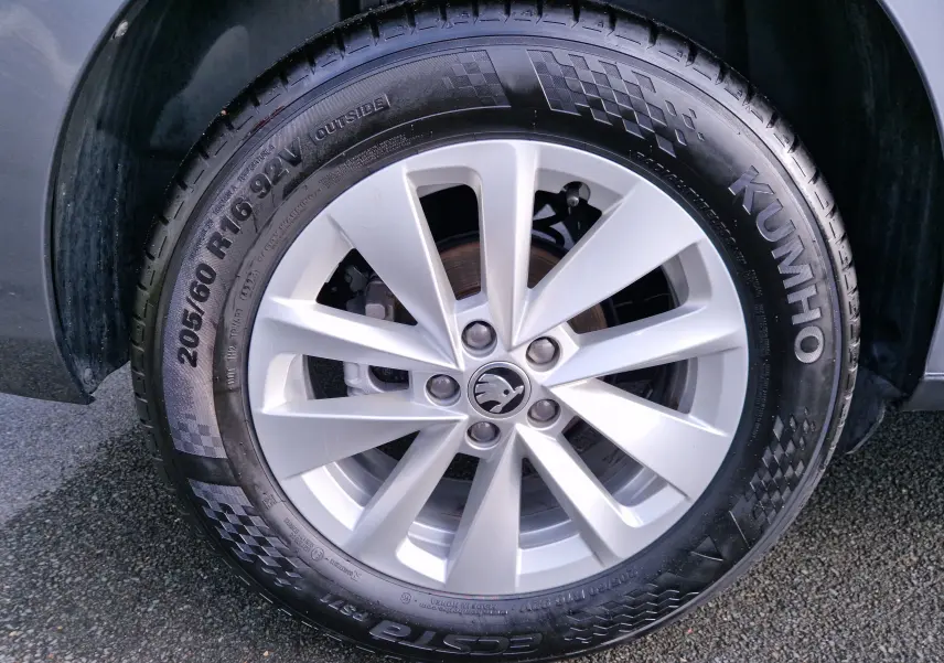 Gros plan sur la jante argentée avec logo Skoda d'un KAMIQ gris graphite, mettant en valeur le pneu Kumho 205/60 R16.