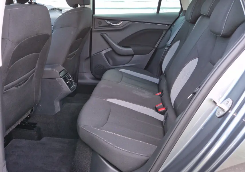 Vue intérieure côté gauche des sièges arrière en tissu gris noir du Skoda Kamiq 2024 gris graphite métal avec porte ouverte.