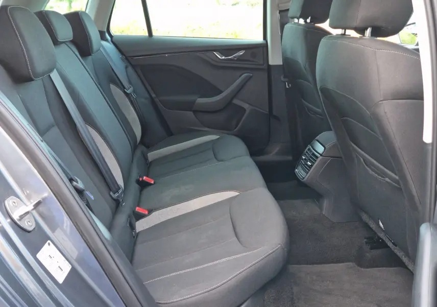 Vue intérieure côté arrière gauche du Skoda Kamiq gris graphite, montrant les sièges arrière en tissu noir et gris.