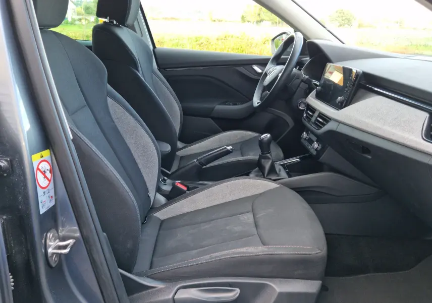 Vue intérieure côté conducteur du Skoda Kamiq gris graphite métal 2024 avec sièges tissu gris et console centrale moderne.