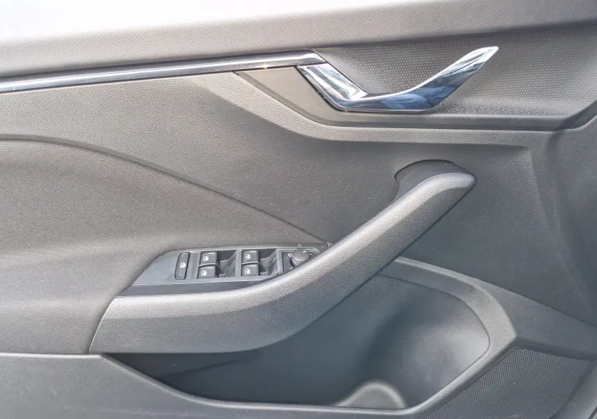 Gros plan sur la poignée intérieure côté gauche de la porte d'une Skoda Kamiq gris graphite avec commandes des vitres et verrouillage.