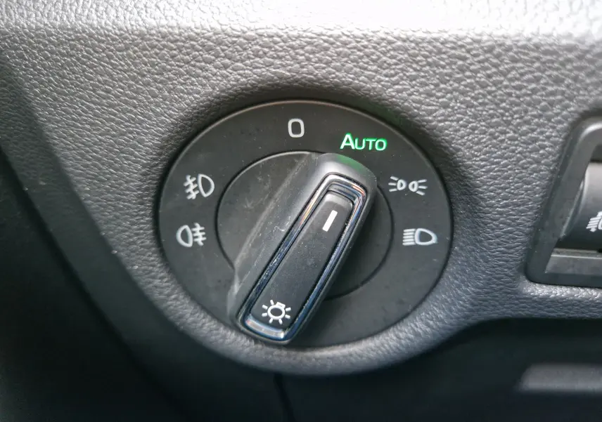 Gros plan sur le sélecteur de phares noir du Skoda Kamiq 2024 gris graphite, affichant le mode automatique activé en vert.