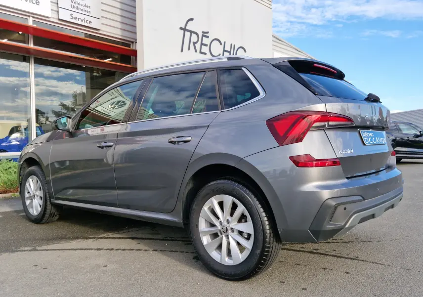 Vue 3/4 arrière droite d'un Skoda Kamiq gris graphite métallisé garé devant un garage avec feux arrière LED visibles.