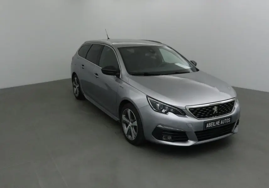 Peugeot 308 SW gris Artense vue 3/4 avant droit, avec jantes alliage et calandre noire distinctive.