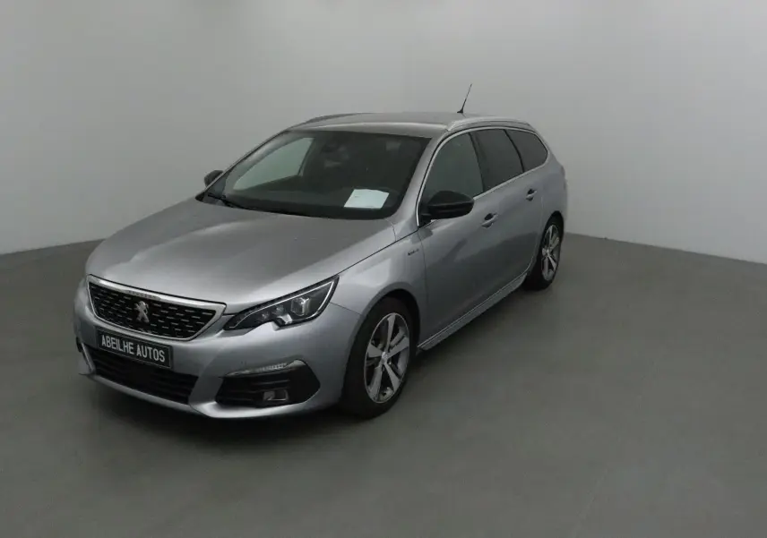 Peugeot 308 SW gris Artense vue 3/4 avant droit dans un studio, avec jantes alliage et calandre noire.