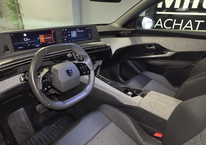 Vue intérieure côté conducteur du Peugeot 3008 2025 avec tableau de bord numérique et sellerie tissu gris et noir.