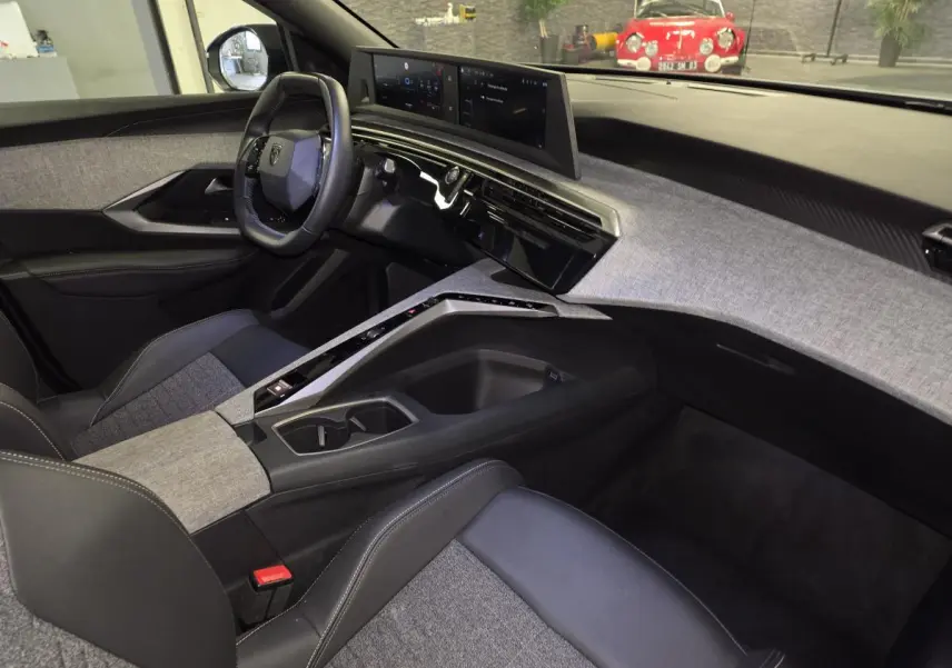 Intérieur avant droit du Peugeot 3008 gris 2025, avec tableau de bord tissu Rimini et double écran HD flottant.
